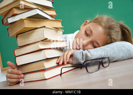 Müde Schule Mädchen schlief auf dem Tisch unter Bücher. Foto von Mädchen in der Schule. Bildung Konzept Stockfoto