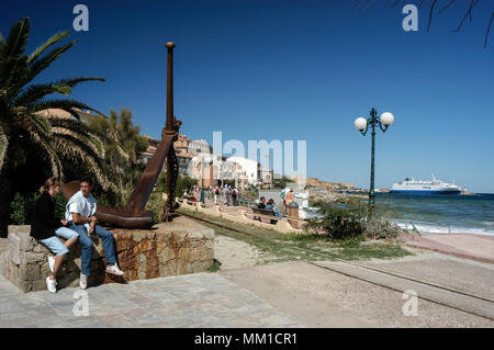 Ein paar sitzen auf einer Mauer an der Promenade de La Marinella in Ile Rousse in der Nähe von Calvi auf der Insel Korsika vor der Südküste von Frankreich. In der backgroun Stockfoto