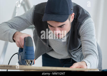 Mann Schneidstoff mit Stichsäge Stockfoto