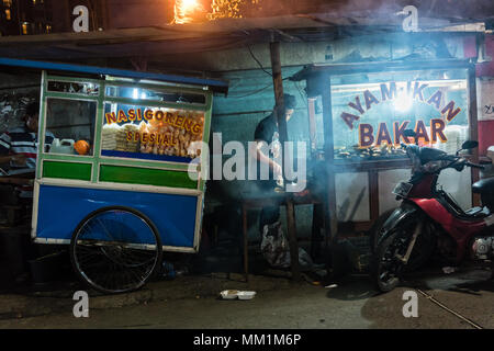 Zwei Straßenhändler, die frisch gegrillten Fisch und verschiedenen Snacks Stockfoto