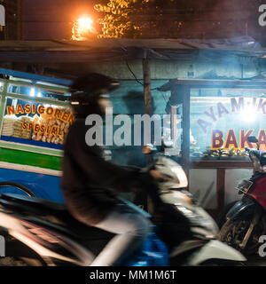 Mann, einen Roller auf einer Straße mit Ständen in einem armen Viertel von Jakarta Stockfoto