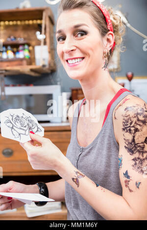 Porträt einer modischen Frau glücklich für die Wahl von zwei Rosen für Ihr neues Tattoo Stockfoto