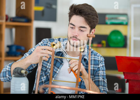 Klempner arbeiten mit einem Brenner erwärmt sich Kupferrohre Stockfoto