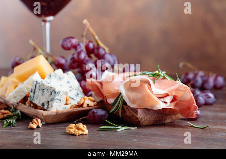 Prosciutto mit verschiedenen Käse, Trauben und Walnüssen auf einem alten Holztisch. Kopieren Sie Platz. Stockfoto