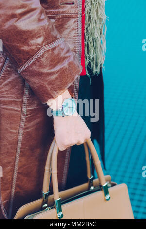 Elegante Frau tragen Silber Armbanduhr und braunem Leder, Fell, Leder braun Handtasche. Vor blauem Hintergrund Stockfoto