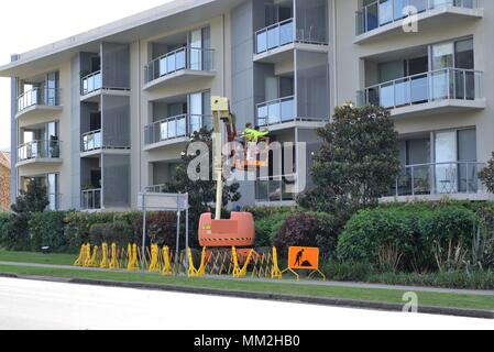 Männer Instandsetzung der Gebäude in Australien, Coffs Harbour. Arbeitnehmer stehen auf Kran Wartungs- oder Malerarbeiten an der Wand. Stockfoto