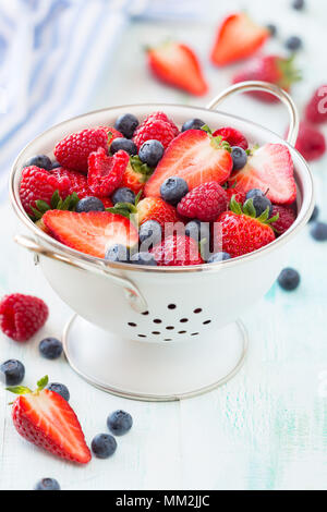 Frische Beeren - Erdbeeren, Himbeeren und Heidelbeeren - in ein Sieb auf weißem Holz- Hintergrund Stockfoto