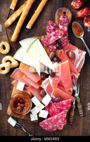 Wurst- und Käseplatte der traditionellen spanischen Tapas, Chorizo, salsichon, Jamon Serrano, Lomo und Scheiben Ziegenkäse - auf hölzernen Eber serviert. Stockfoto