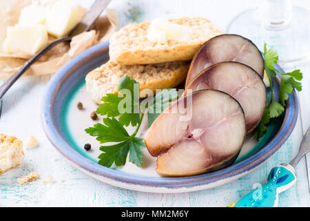 Ausgehärtete Makrele in Scheiben schneiden und serviert mit frischer Petersilie und Brot auf weißem Holz- Hintergrund Stockfoto