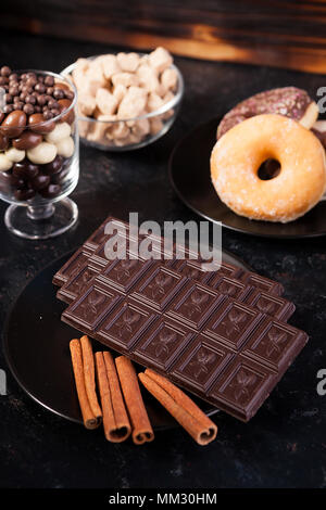 Blick von oben auf die Schokolade Tabletten, Donuts, brauner Zucker mit Erdnüssen in Schokolade und Kaffee Bohnen Stockfoto