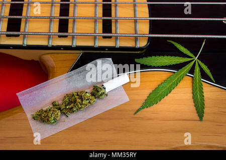 Gemeinsame bereit zu rollen und Marihuana Blatt auf Vintage E-Bass mit vier Saiten. Musikinstrumente und Drogen, Konzept der Suchen nach Inspiration. Stockfoto