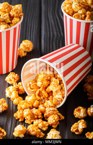 Sweet caramel Popcorn in Pappbechern close-up auf der Schwarzen Tisch. Vertikale Stockfoto