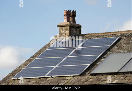 Solarzellen auf dem Dach eines Hauses neben traditionelle Schornstein Töpfe. North Dorset England UK Stockfoto