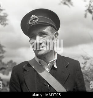 1950, historische, Porträt einer männlichen GPO Arbeitnehmer außerhalb in Uniform und tragen cap Badge, Nordirland, Großbritannien. Stockfoto