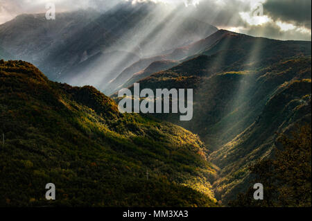 Sonnenstrahlen durch die Wolken in einer bergigen Tal Stockfoto