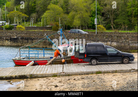 Fischer malt sein Boot, das zu einer Helling in Bantry, County Cork, Irland gebunden ist. Stockfoto