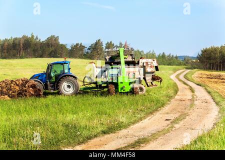 Natürlicher Dünger agro bio Befruchtung. Laden von Mist am Traktor. Landwirtschaftliche Landschaft in der Tschechischen Republik Stockfoto