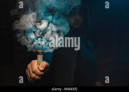 Tropfer in einer Hand eine Wolke aus weißen, blauen Dämpfen. Freundlich für vape shop Poster und Design. Vaping Konzept. Stockfoto