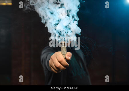 Tropfer in einer Hand eine Wolke aus weißen, blauen Dämpfen. Freundlich für vape shop Poster und Design. Vaping Konzept. Stockfoto