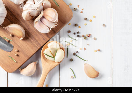 Knoblauch und Rosmarin Blätter auf Holz Löffel mit Pfeffer auf weißem Holz Hintergrund, Ingredient essen und Kraut Konzept Stockfoto