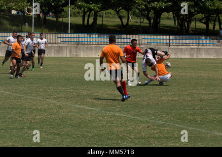 Joensuu, Okinawa, Japan - ein Camp Hansen Kaiju player wird durch Spieler ein Okinawa Sun Schweine", die im Rahmen der 4. jährlichen Schlacht in Angriff genommen, die auf dem Felsen Rugby Turnier am Zanpa Ball Park Sept. 2 in Joensuu, Okinawa, Japan. Die Teams zeigten ein hohes Maß an Teamwork, Fairness und Wettbewerbsfähigkeit. Rugby ist ein Kontakt Team Sport, die in England in der ersten Hälfte des 19. Jahrhunderts entstanden. Stockfoto