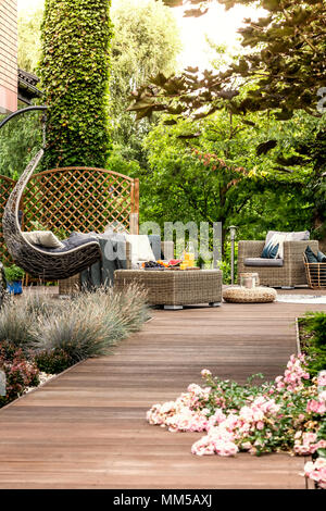 Hängesessel und Gartenmöbeln auf einem hölzernen Terrasse in einem entspannenden Resort Stockfoto