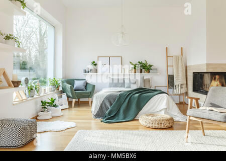 Geräumige, möblierte Schlafzimmer mit Bett, Kamin, Stuhl, Sessel, Teppich und Ornamente Stockfoto