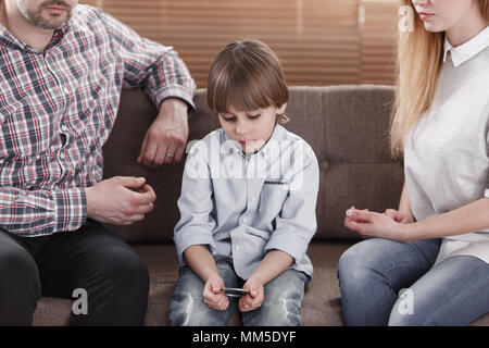 Nahaufnahme der traurige junge mit Autismus zwischen besorgt, Mutter und Vater sitzen Stockfoto