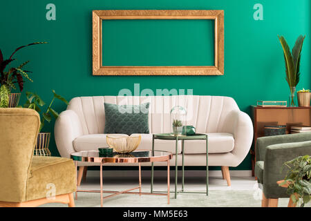 Metall gold und grün Tabellen in Wohnzimmer Einrichtung mit hellen Couch und leeren mockup Frame Stockfoto