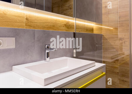 In der Nähe von Waschbecken mit Wasserhahn gegen Grau und die Holzwand in eleganten Bad Interieur Stockfoto