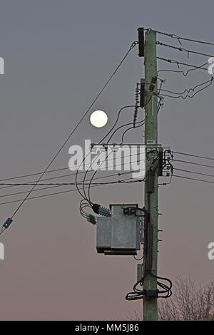 Blick auf den Mond neben dem Strommast mit Transformator Stockfoto