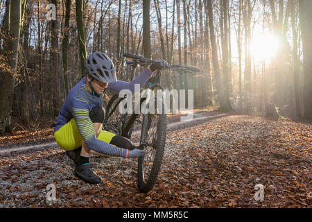 Biker zur Festsetzung Vorderrad seines Fahrrades auf Waldweg, Bayern, Deutschland Stockfoto