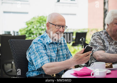Ältere Menschen mit Smartphone am Frühstückstisch Stockfoto