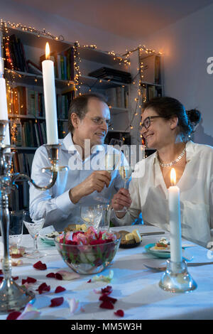 Paar Toasten mit Champagner Gläser auf ein Abendessen bei Kerzenschein Stockfoto