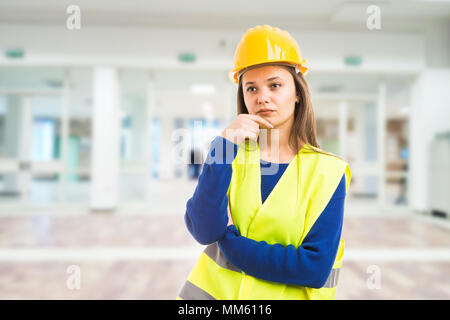 Junge attraktive Ingenieurin denken als nachdenkliche Meditation für Lösung Konzept auf Indoor lobby Gebäude Hintergrund Stockfoto