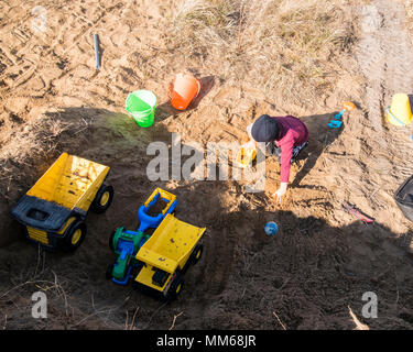 Wenig junge spielt mit seinem Lkw in einem Haufen von Schmutz. Stockfoto