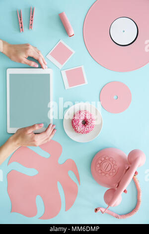 Ansicht von oben ein blauer Schreibtisch mit Vintage Telefon, Blatt, Donut, Vinyl und Hände berühren eines Tablet Stockfoto