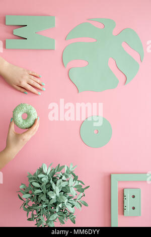 Mint Farbe Blatt, cd, Anlage und einer Frau mit einem Krapfen auf einem rosa Hintergrund Stockfoto