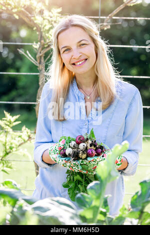 Gartenarbeit - Frau hält frische bio Radieschen in Ihren Händen Stockfoto