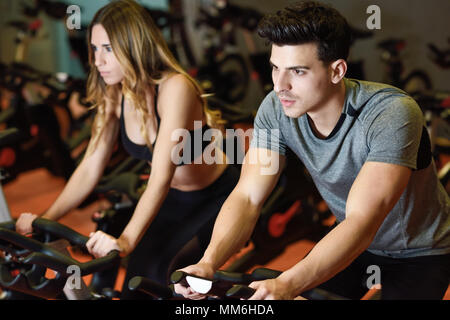 Junger Mann und Frau Radtouren in der Turnhalle, die Beine tun cardio Workout radfahren Fahrräder. Zwei Personen in einem sich drehenden Klasse Sportkleidung zu tragen. Stockfoto