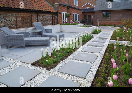 Symphonie verglaste Pflastersteine Form den Weg zu dem Haus, mit Tulipa Tulipa 'Kokette' und 'Pink Diamond' entweder Seite. Credits: Design von Zinnia Stockfoto