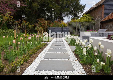 Symphonie verglaste Pflastersteine Form einen Weg zu einem Whirlpool mit Tulipa 'Pink Diamond' und Tulipa 'Kokette' entweder Seite. Credits: Design von Zinn Stockfoto