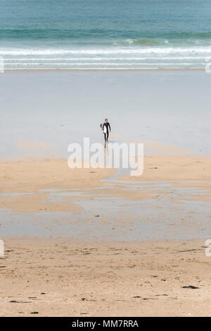 Ein einsamer Surfer sein Surfbrett tragen und von dort über Fiostral Strand in Newquay in Cornwall; Stockfoto