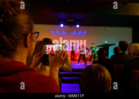 Eine Frau nimmt eine Schule Konzert mit einem iphone Stockfoto