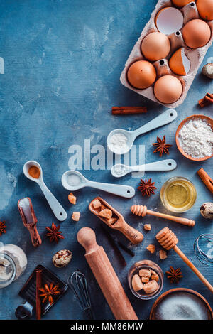 Kochen Werkzeuge und Zutaten von oben. Backen Konzept mit Messlöffel, Holz- Schaufeln, wischt, Ausstechformen, Zucker, Mehl, Eier und Zimt Stockfoto