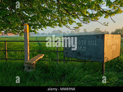 Öffentlichen Fußweg und Holm über einen Metallzaun mit einem Bauernhof Zeichen in ländlichen Engalnd Stockfoto