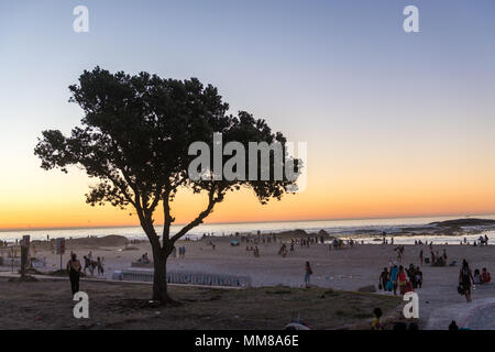 Gruppen von Menschen auf einem Strand in Camps Bay bei einem schönen Sonnenuntergang in Kapstadt, Südafrika Stockfoto