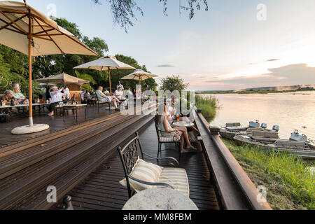Eine Gruppe von Hotel die Gäste des Royal Livingstone Hotel auf der Sonnenterrasse sitzen und den Sonnenuntergang über dem Sambesi Livingstone, Sambia beobachten Stockfoto