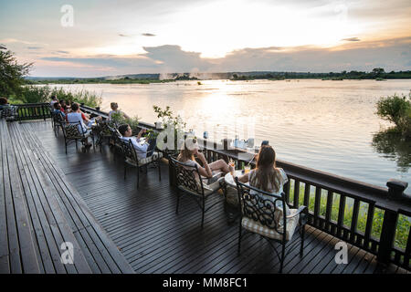 Eine Gruppe von Hotel die Gäste des Royal Livingstone Hotel auf der Sonnenterrasse sitzen und den Sonnenuntergang über dem Sambesi Livingstone, Sambia beobachten Stockfoto