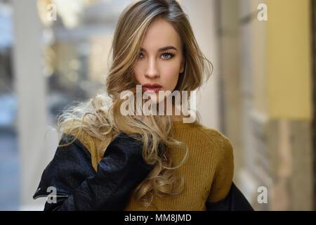 Blonde Frau im städtischen Hintergrund. Schöne junge Mädchen mit schwarzen leder jacke und mini rock auf der Straße stand. Hübsche Russische Frauen mit Stockfoto